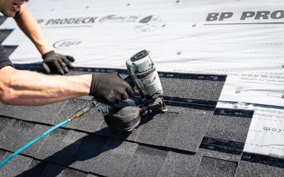 Close-up of a roofer using a nail gun to secure roofing shingles in place.