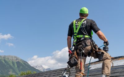 Roofer standing on a roof, securing shingles with a Cranbrook mountain view in the background.