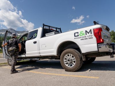 Worker in front of a C&M Roofing Ltd truck, preparing to enter the vehicle with mountains in the distance.