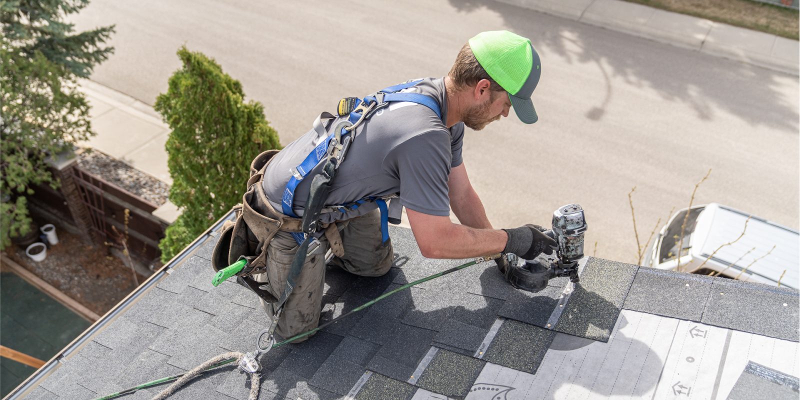 Person on roof nailing shingles.